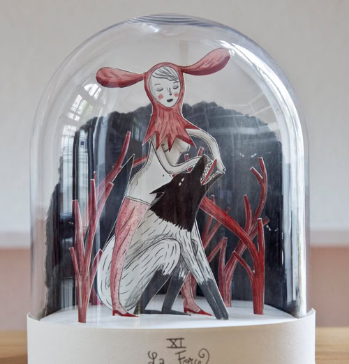 L’illustratrice et bédéiste lausannoise propose une création délicate autour des symboles du tarot, revisités par le biais du dessin et de découpages mis en scène sous des cloches de verre.