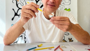 Main dessin d'une pierre précieuse en cours de coloriage avec des crayons de couleur, une main tenant un crayon orange.