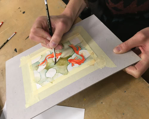 Peintures de visages de chats avec de grands yeux colorés, principalement violets et verts, disposées sur une surface.