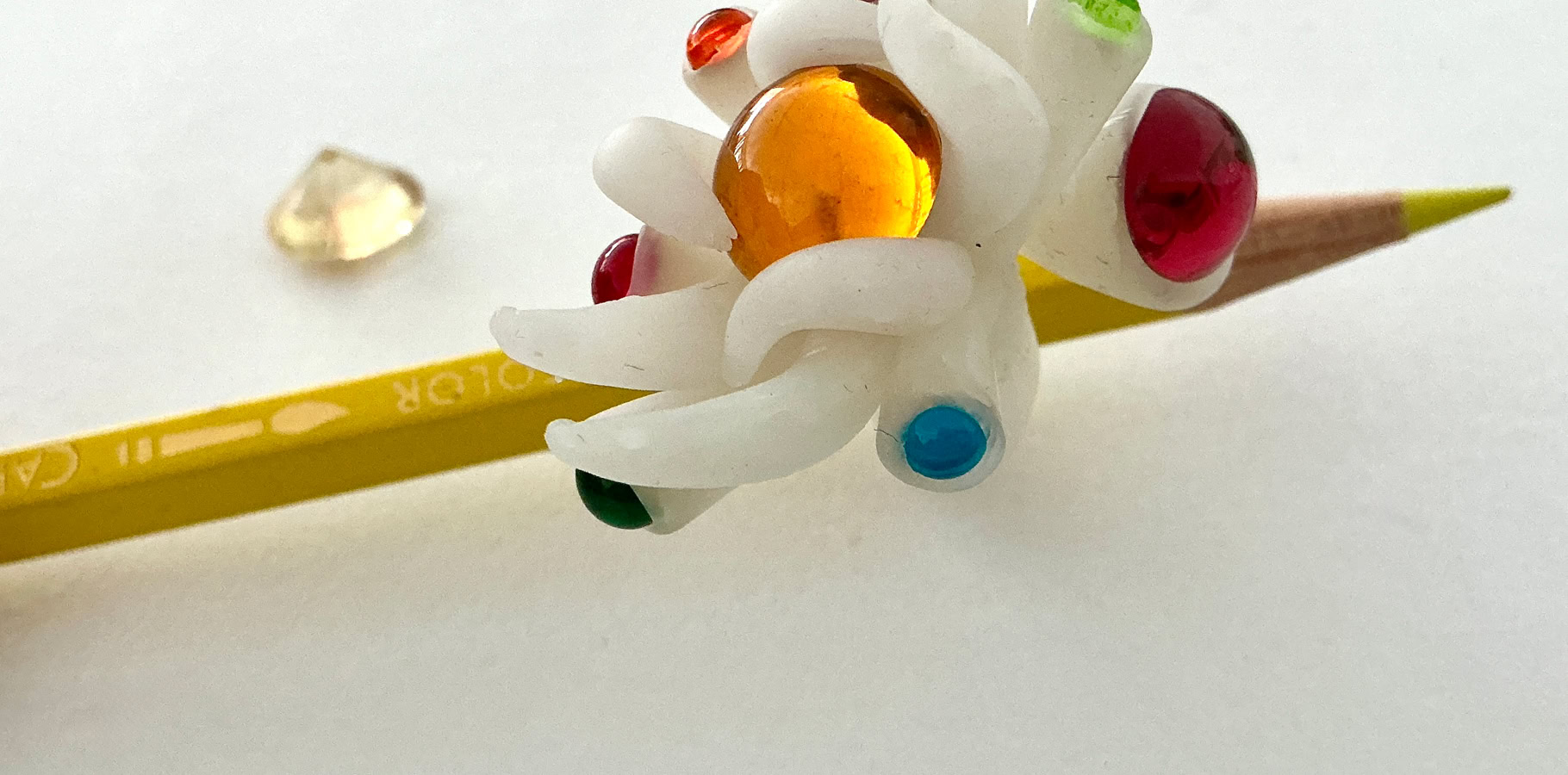 Artiste assis à une table avec des crayons de couleur et des dessins, fond artistique en noir et blanc.