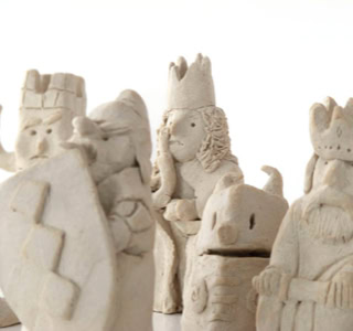 Figurines en argile représentant des personnages avec des couronnes et des accessoires, sur fond blanc.