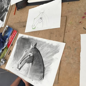 Dessins de chevaux sur une table, avec des crayons et des chiffons à proximité.