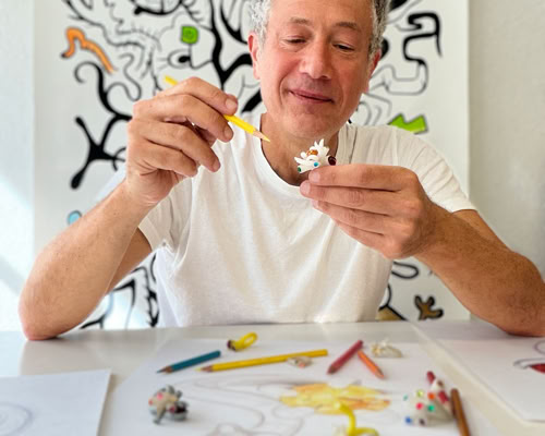 Main dessin d'une pierre précieuse en cours de coloriage avec des crayons de couleur, une main tenant un crayon orange.