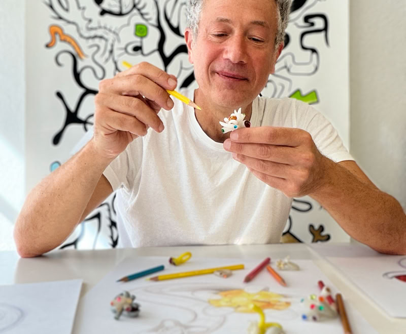 Main dessin d'une pierre précieuse en cours de coloriage avec des crayons de couleur, une main tenant un crayon orange.