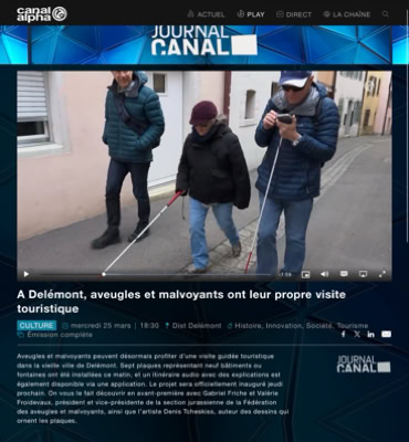Trois personnes marchant dans la rue, deux utilisant des cannes blanches.