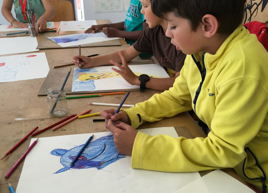 Des enfants assis à une table en train de dessiner avec des crayons de couleur.