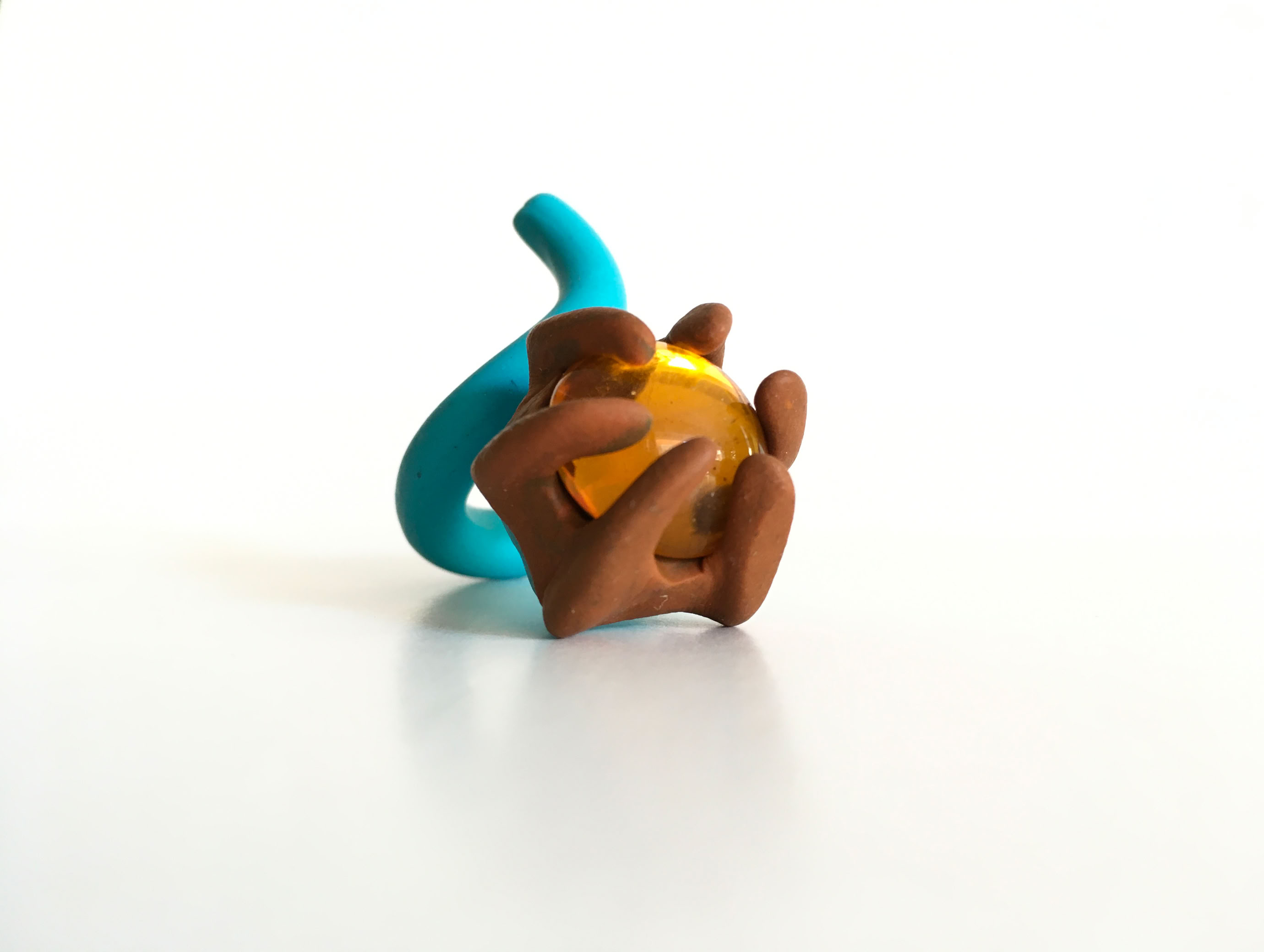 Sculpture abstraite en pâte à modeler avec des formes marron et bleues autour d'une sphère jaune.