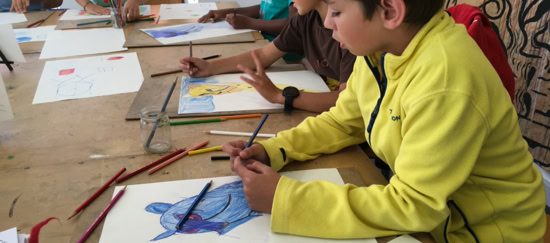 Des enfants assis à une table en train de dessiner avec des crayons de couleur.