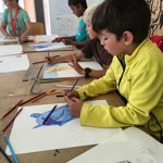 Des enfants assis à une table en train de dessiner avec des crayons de couleur.